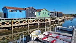 Une jetée en bois bordée de maisons en bois aux couleurs vives, un quai avec des bateaux et une eau calme.