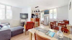 Un espace de vie compact comprenant un canapé, une table à manger avec des chaises, un coin cuisine avec un réfrigérateur, un four à micro-ondes et un téléviseur.