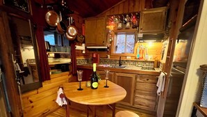 A cozy kitchen with wooden cabinets, a round wooden table, two stools, and a wine bottle. - Private Mtn Love Shack w/ fast wifi, BBQ & view (Franklin)