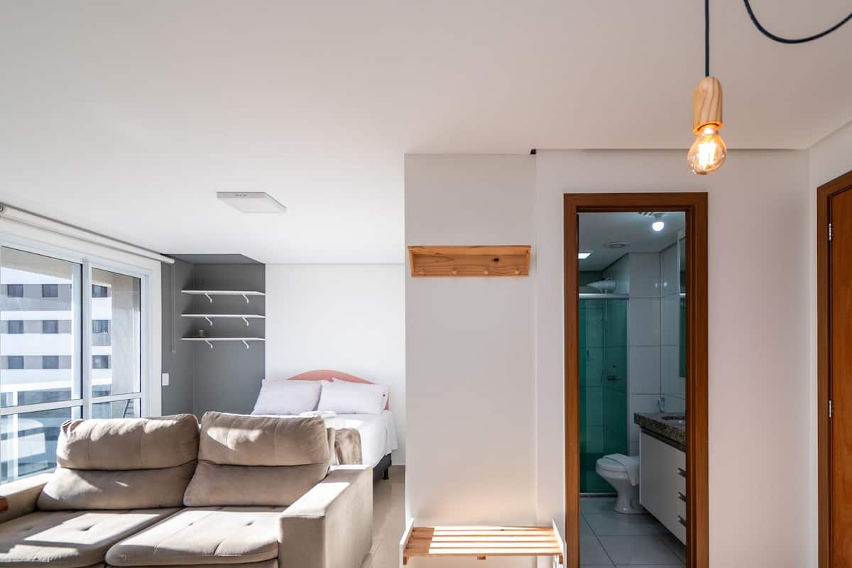 A modern apartment with a sofa, a bed, and a wooden shelf.