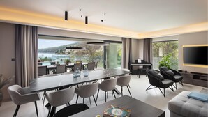 Una sala moderna con comedor, un piano y un televisor grande.