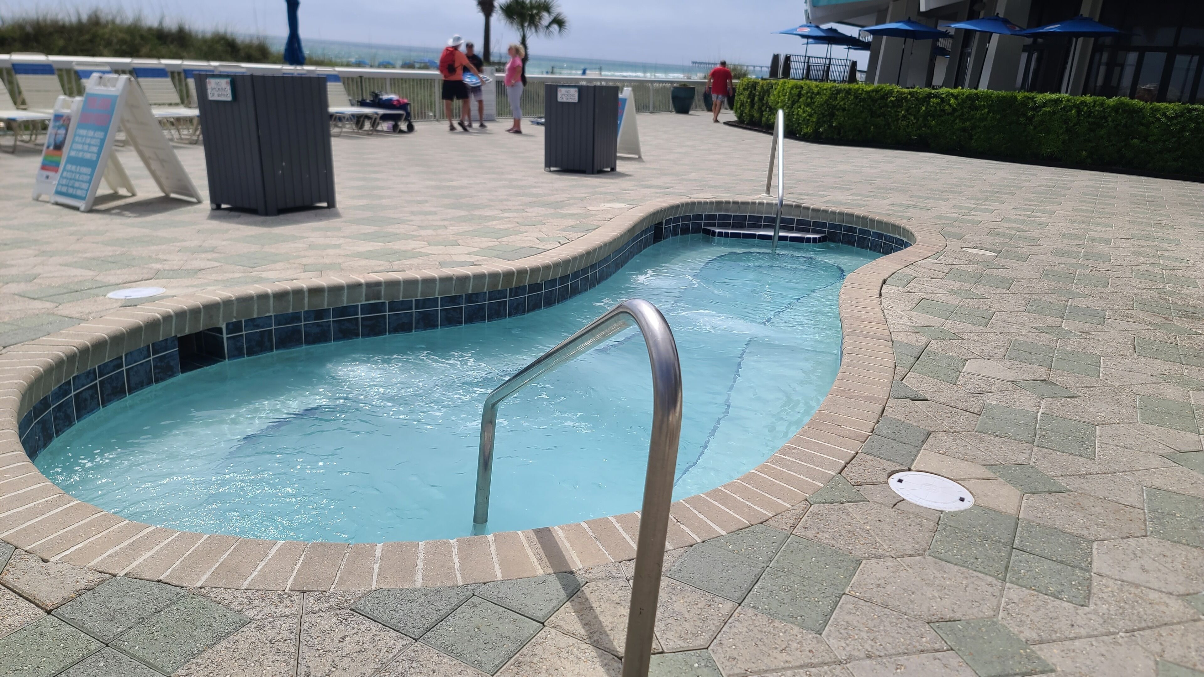 Una piscina con escalera metálica, rodeada por un solárium con baldosas hexagonales.