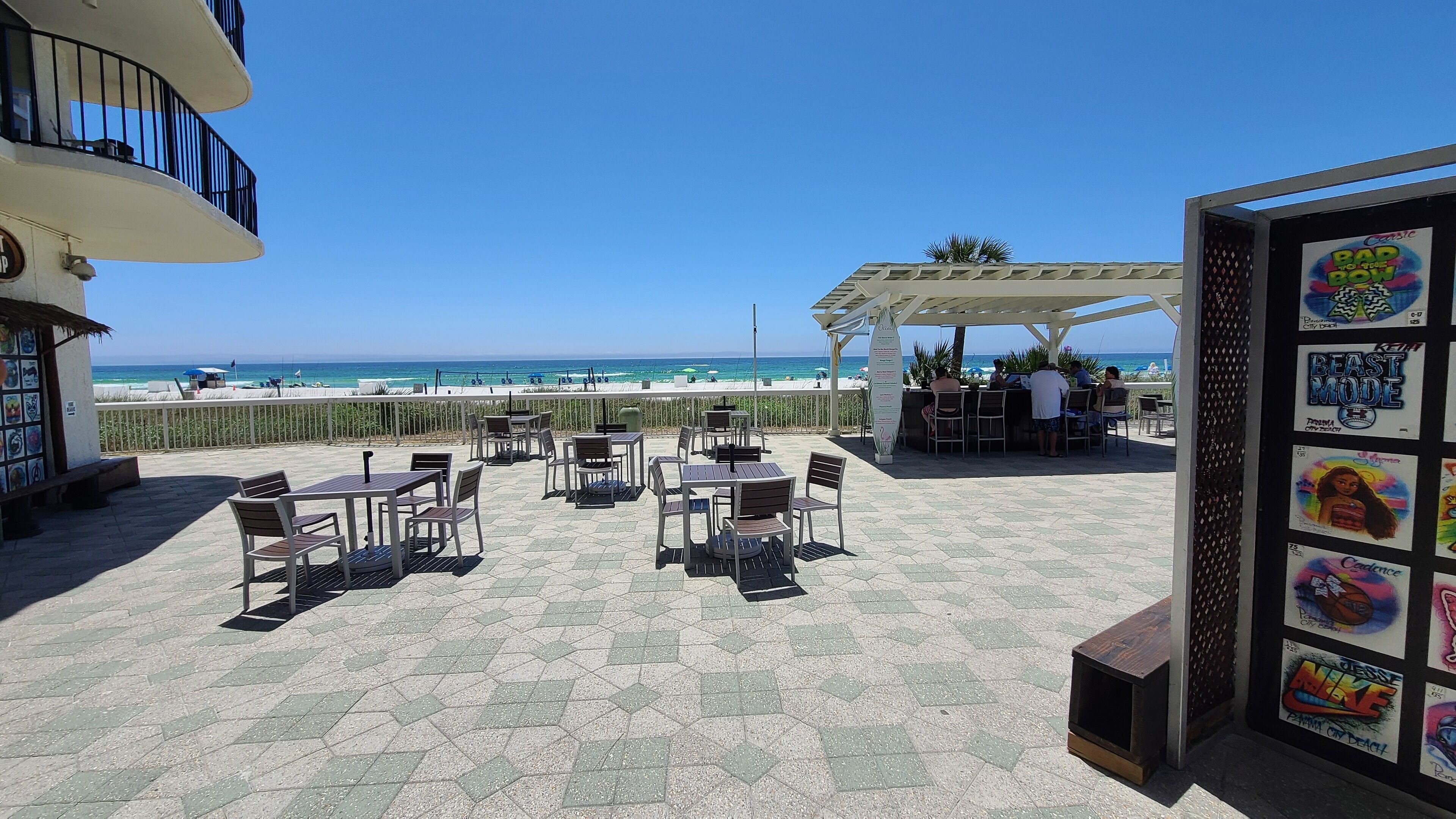 A terrace with tables and chairs, overlooking the beach.