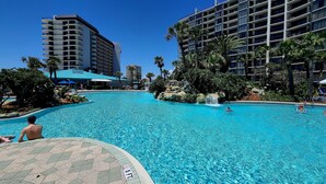 A large outdoor swimming pool with clear blue water, surrounded by palm trees and modern buildings. - Beachfront  Private Balcony 
 Edgewater Beach Resort
 Best Gulf Views (Panama City Beach)