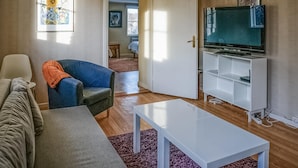 A living room with a sofa, armchair, coffee table, TV, and artwork on the walls. - 5 bedroom nice home in Kilsmo (Kilsmo)