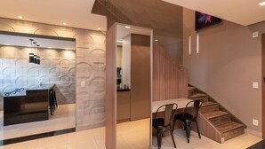 A modern interior with a kitchen area, a dining space, and a staircase. - Modernos Flats no Setor Bueno TXP03 (Goiânia)