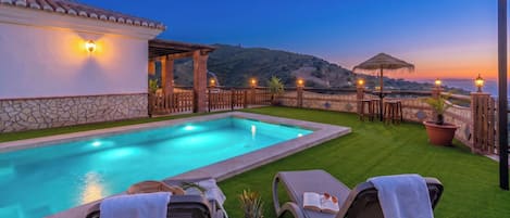 A swimming pool with lounge chairs and a view of the hills.
