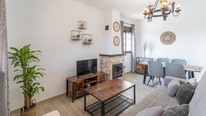 A living room with a TV, fireplace, dining area, and a large plant. - Casa La Solana Torrox by Ruralidays (Málaga)