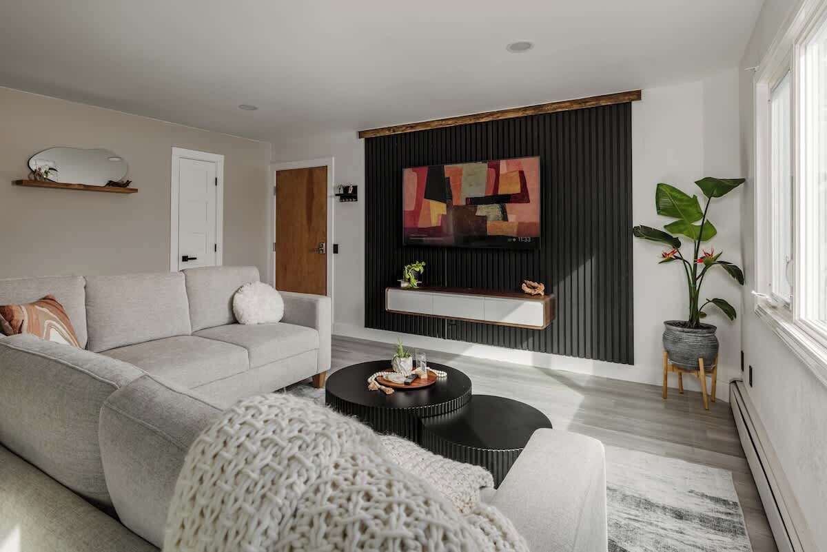Ein modernes Wohnzimmer mit einem grauen Sofa, einem schwarzen Couchtisch und einem großen, abstrakten Gemälde an der Wand.