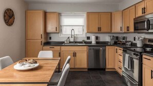 Une cuisine moderne avec des meubles en bois, un lave-vaisselle en acier inoxydable et un four à micro-ondes.