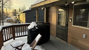 Un espacio al aire libre techado con un piso de madera, un bote de basura y un banco.