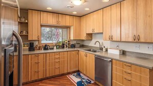 Una cocina moderna con armarios de madera, electrodomésticos de acero inoxidable y un ventanal que proporciona luz natural.