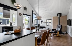 A modern kitchen with a central island, dining area with chairs, a sofa, and a fireplace. - Pet friendly home in Hemmet with WiFi (Hemmet)