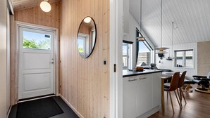 A modern kitchen with white cabinets, a wooden wall, and a large window.