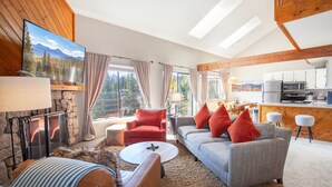 Ein großzügiges Wohnzimmer mit Kamin, einer Sofagarnitur, einem Couchtisch und einer Küchenzeile mit modernen Geräten.