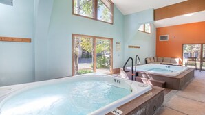 Un espace détente avec deux bains à remous, un banc en bois et une vue sur l’extérieur.