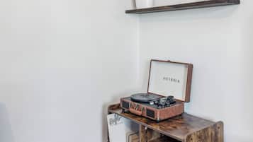 A corner with a wooden desk, a vintage record player, and a plant on a shelf.
