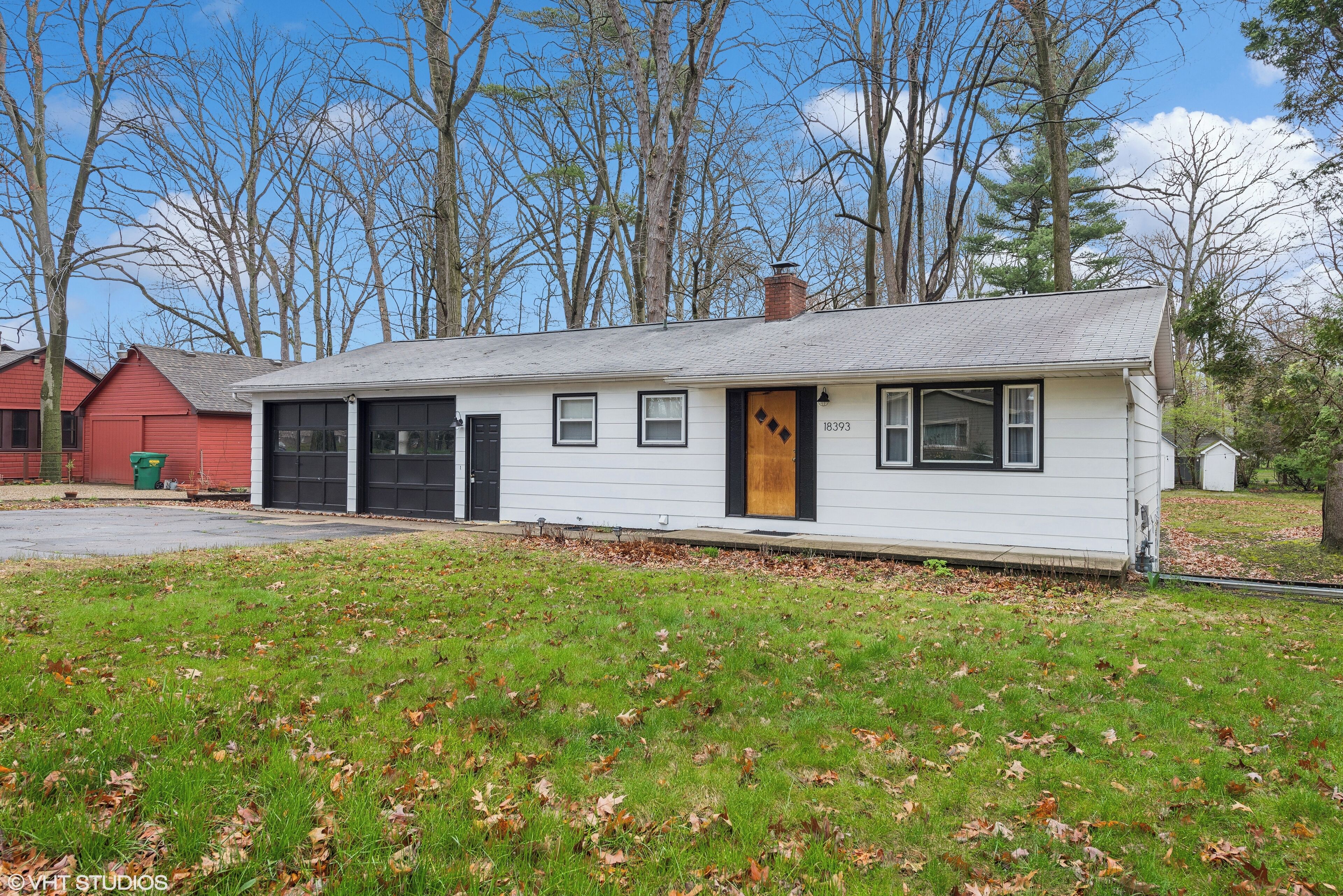 A single-story white house with a black front door, a garage, and a small porch.