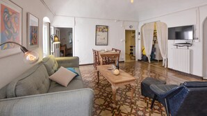 Een woonkamer met een bank, een salontafel, een eettafel en een televisie.