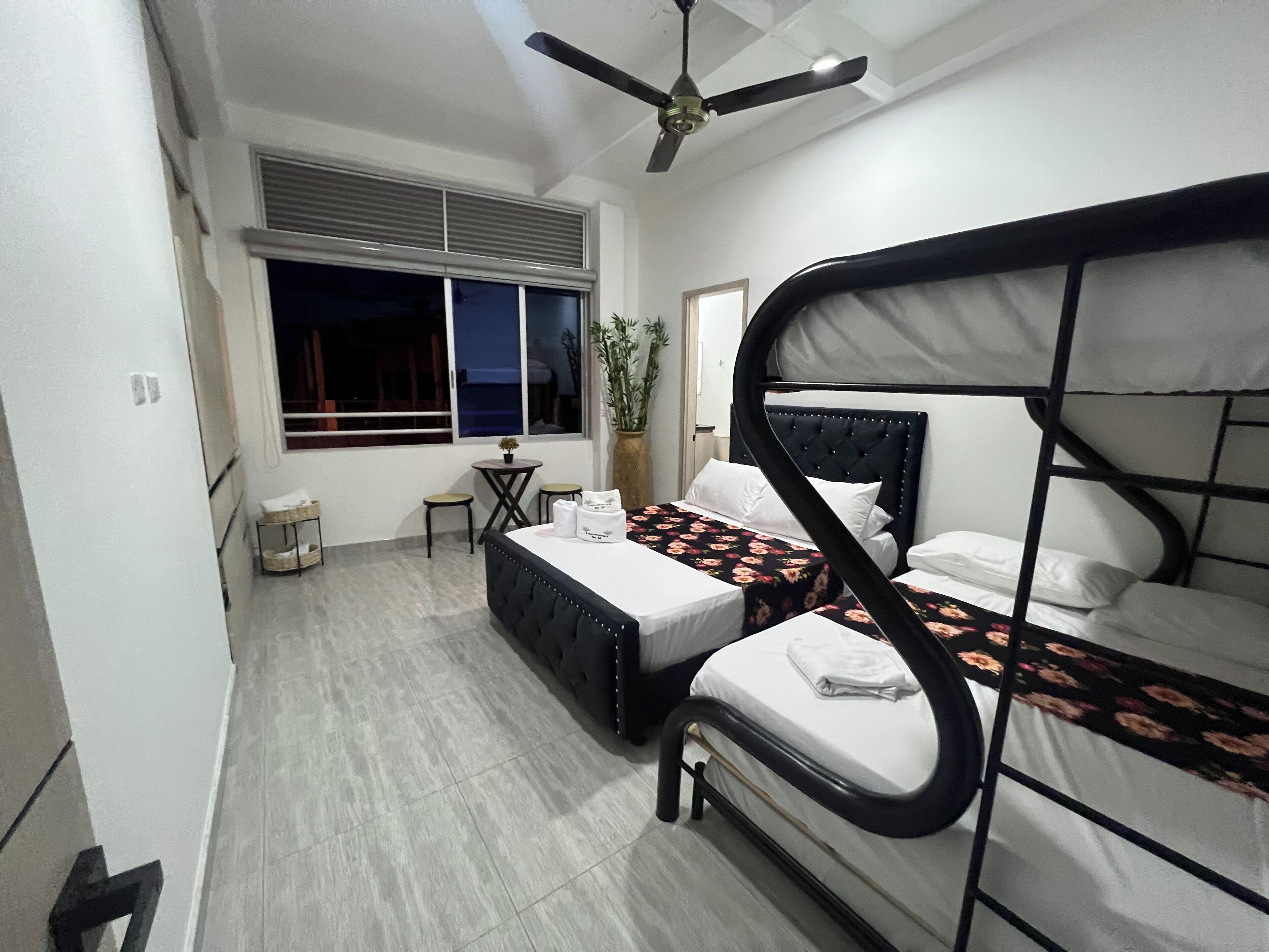 A bedroom with bunk beds, a small table, and a window with blinds.