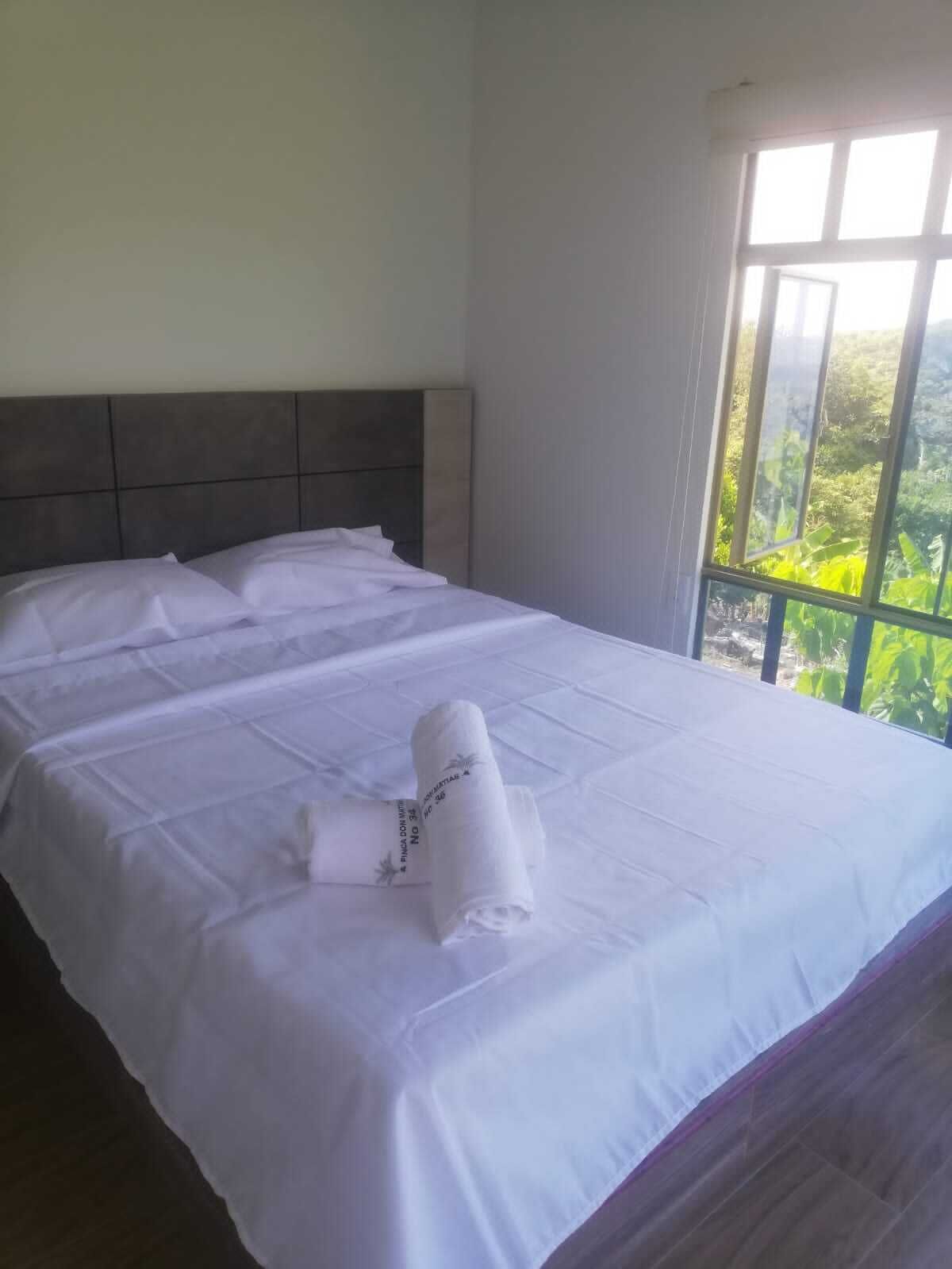 A neatly made bed with white linens and a rolled towel placed on it.