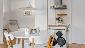 Een moderne keuken met witte kasten, een ronde eettafel en een hangende pannendroger.