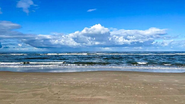 Una playa con cielo despejado y olas.