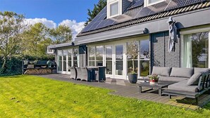 Una casa moderna con una terraza amplia, un comedor y una sala de estar con un sofá y una mesa.