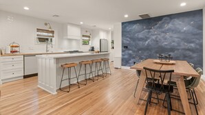 A modern kitchen with a wooden island, bar stools, and a dining table with chairs. - Luxury 3BD 2bath Near EXPO & TU (Tulsa)