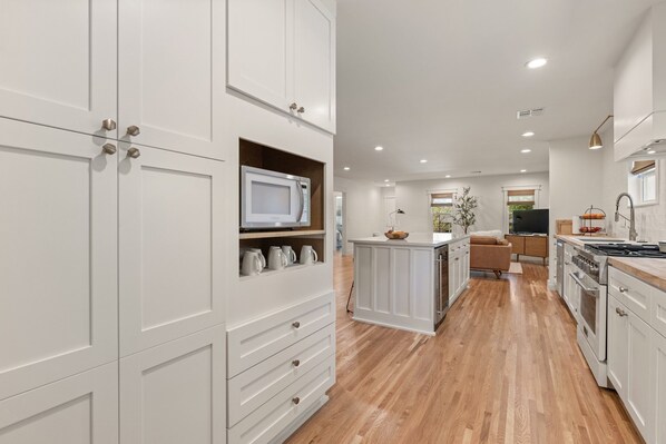 A modern kitchen with white cabinetry, a built-in microwave, and a central island with seating. - Luxury 3BD 2bath Near EXPO & TU (Tulsa)