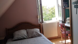 Ein Schlafzimmer mit Bett, Fenster und Heizkörper.