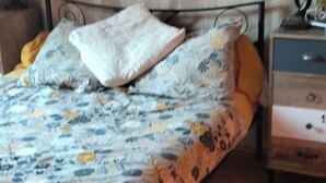 Makuuhuoneessa on sänky, yöpöytä, lamppu ja seinällä taulu.