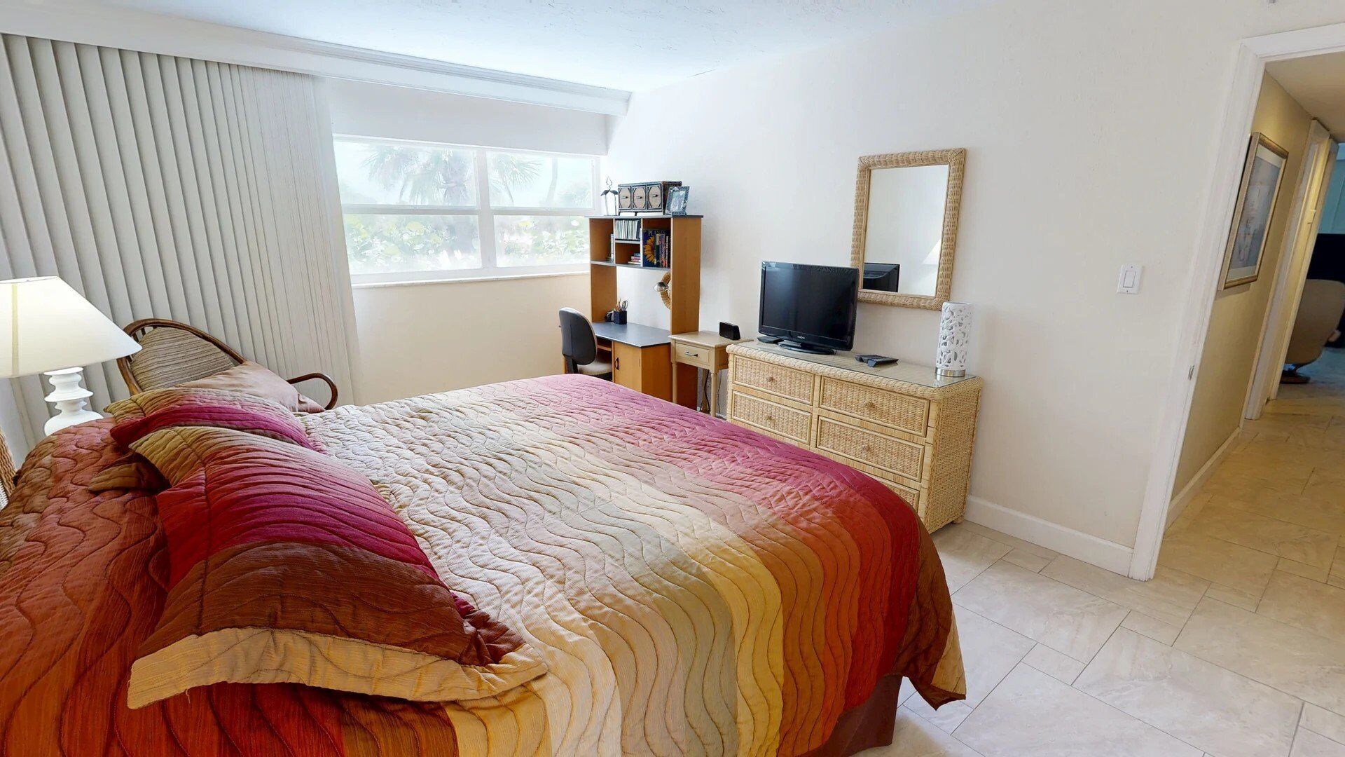 A hotel room with a bed, a desk, a television, and a bookshelf.