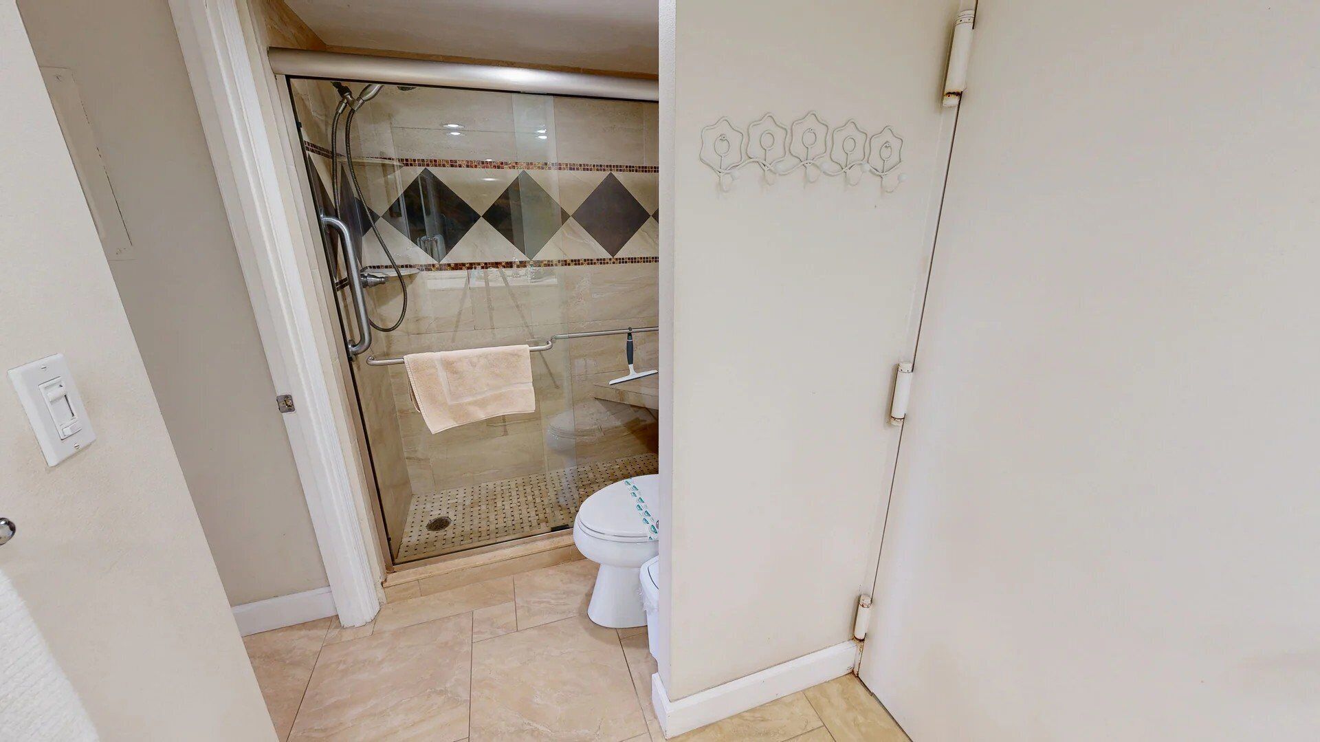 Een badkamer met een douche met glazen wand, een toilet en een handdoekhouder.