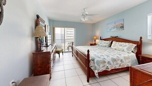 A bedroom with a bed, a desk, a chair, a ceiling fan, and a window with a view of buildings. - Crescent Arms Vacation Rentals 403 N Siesta Key Florida (Siesta Key)