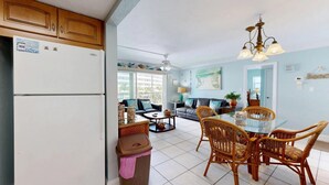 A spacious living area with a dining table, wicker chairs, and a ceiling fan. - Crescent Arms Vacation Rentals 403 N Siesta Key Florida (Siesta Key)