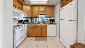 A kitchen with wooden cabinets, a microwave, stove, dishwasher, and a refrigerator. - Crescent Arms Vacation Rentals 403 N Siesta Key Florida (Siesta Key)