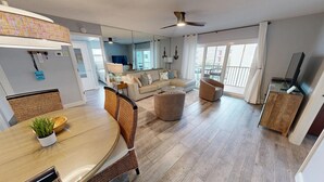 Un salon moderne comprenant un coin repas, un ensemble de canapés, un ventilateur de plafond et un téléviseur.