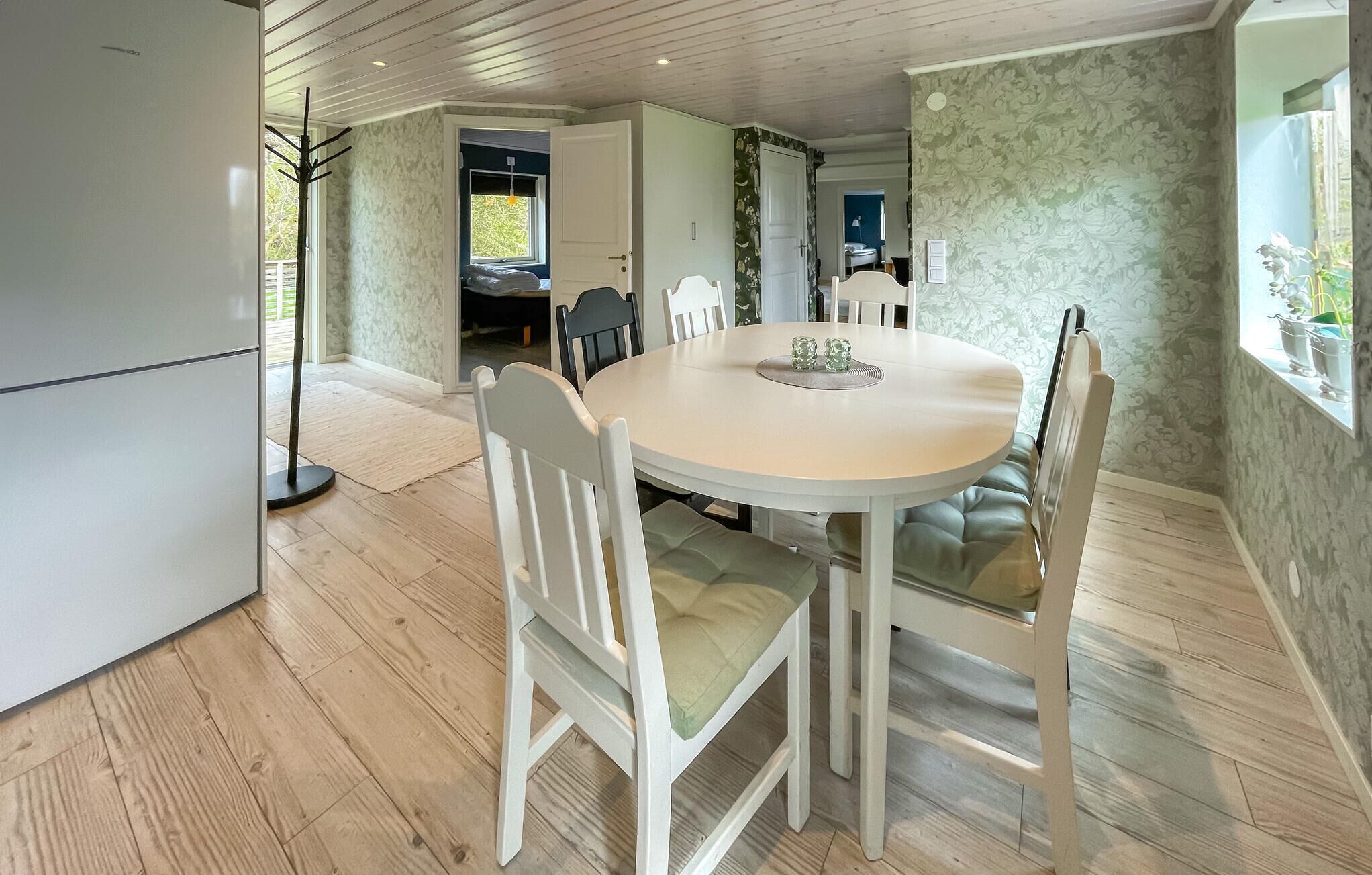 Een eetgedeelte met een ronde tafel, witte stoelen en een lichtgekleurde vloer.