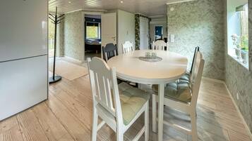 Een eetgedeelte met een ronde tafel, witte stoelen en een lichtgekleurde vloer.