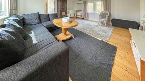 Ein modernes Wohnzimmer mit einem Ecksofa, einem Holztisch und einem gemusterten Teppich.