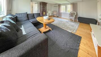 Een moderne woonkamer met een hoekbank, een houten salontafel en een vloerkleed met een patroon.
