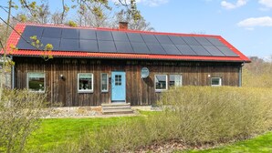 Ein Holzhaus mit rotem Dach und Solaranlage.