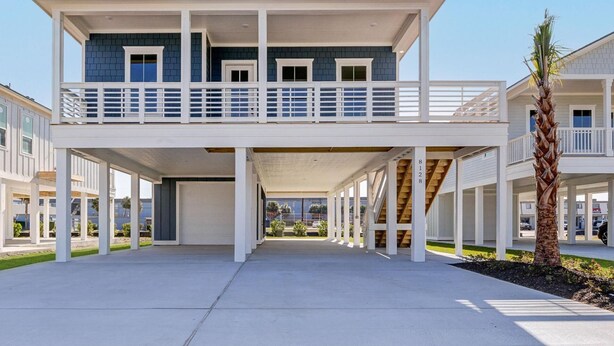 A two-story beachfront house with a balcony, a covered patio, and a view of the ocean. - Salt and Stone Villa 8128 (Galveston)