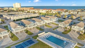 A residential area with multiple two-story houses, a swimming pool, and a tennis court. - Salt and Stone Villa 8128 (Galveston)