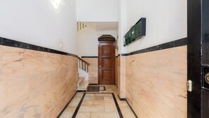 Un pasillo con paredes de mármol y una puerta de madera al final.