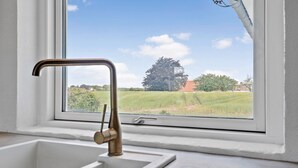 Uma cozinha com vista para um campo verde e uma árvore.