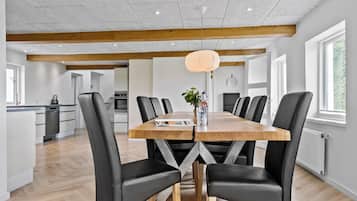 A modern dining area with a wooden table, black leather chairs, and a pendant light.