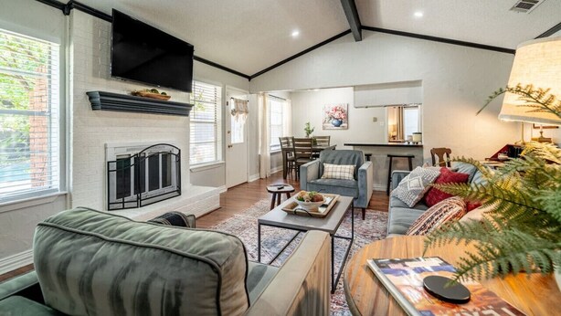 A spacious living room with a fireplace, a television mounted on the wall, and a cozy seating area with a coffee table. - Country Pool House w/ Game Room, Fire Pit, Grill (North Richland Hills)