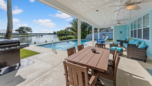 An outdoor patio with a pool, a table and chairs, a grill, and a sofa. - Canal-Front Home with Heated Pool (Cocoa Beach)